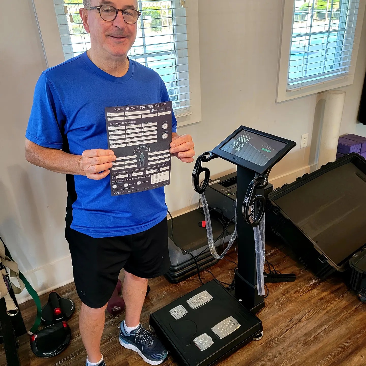 End Rezults Fitness male client holding his Evolt 360 body composition scan report beside the scanner